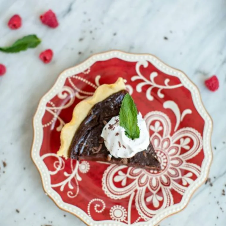 Slice of chocolate cream pie topped with whipped cream and mint
