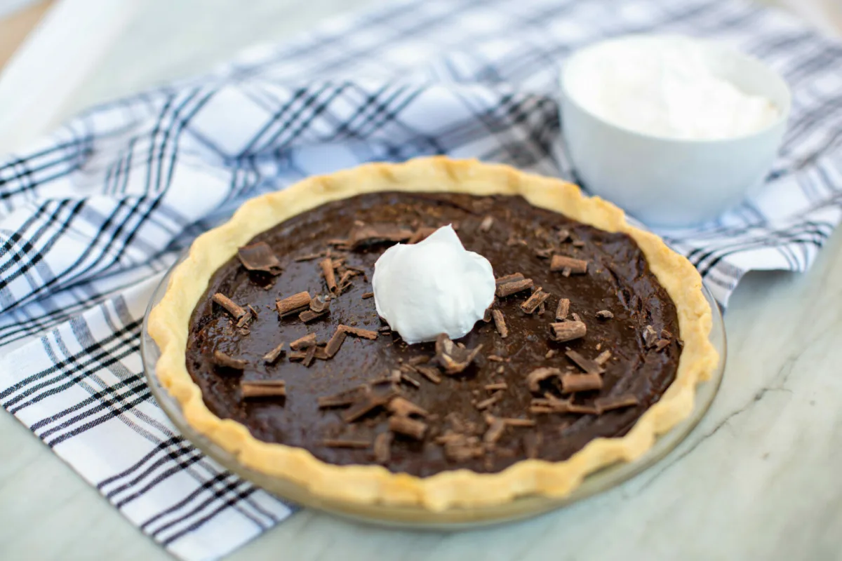 A whole chocolate cream pie with whipped cream and chocolate shavings