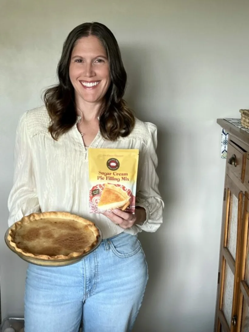 Natalie Warner, owner of Rolling Pin Bakehouse, holding a sugar cream pie and a mix pouch